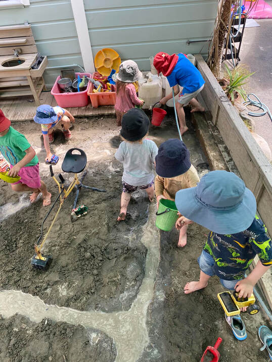 Children using water in trenches they have dug in the sandpit